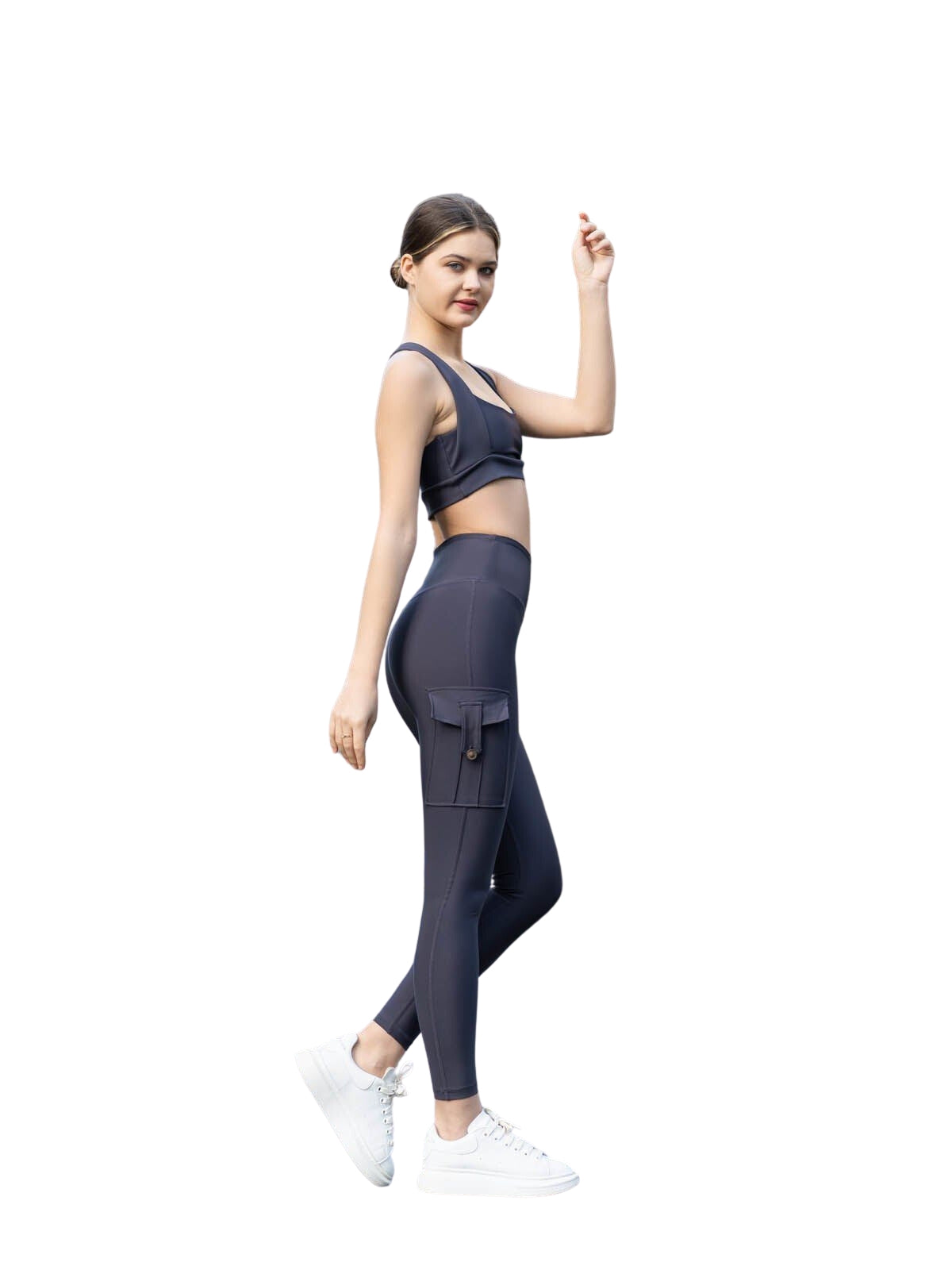 Frau in Lismina Anthrazit 317 Pocket Leggings und weißen Sneakers posiert vor weißem Hintergrund.